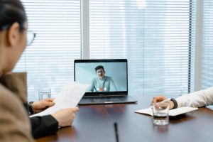 A virtual assistant is discussing with two clients through laptop